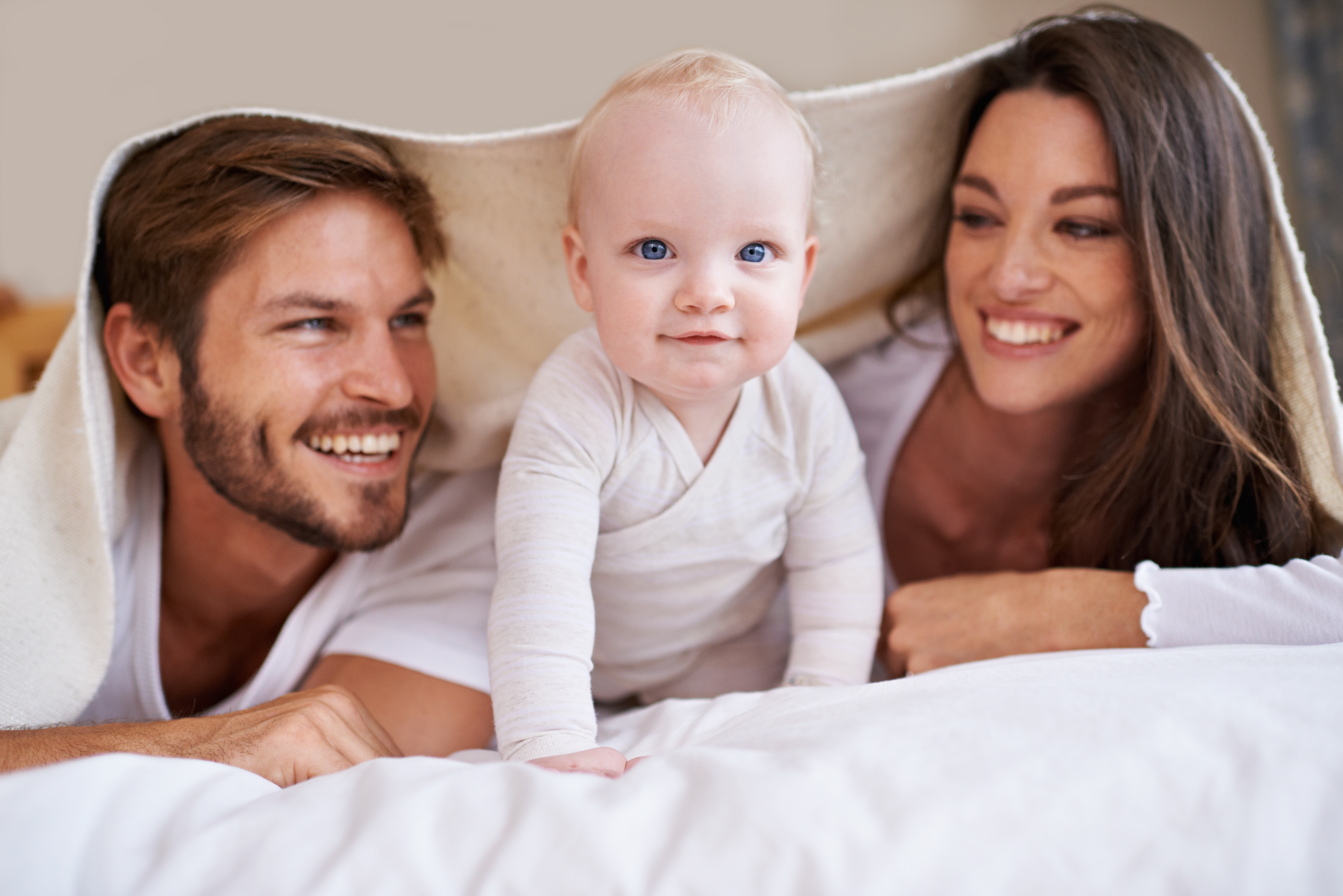 Cropped shot of a young couple lying on the bed with their baby boy